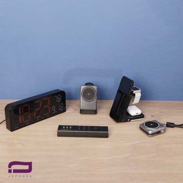 ست مدیریتی K9252 شامل ساعت رومیزی دیجیتال بزرگ با نمایشگر قرمز، استند شارژ وایرلس سه کاره برای گوشی و ساعت، شارژر فندکی چند پورت و پاوربانک مگنتی کوچک روی میز چوبی.